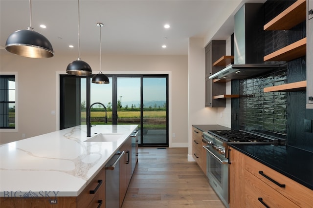 kitchen featuring a large island, stainless steel appliances, tasteful backsplash, dark stone countertops, and light wood-type flooring