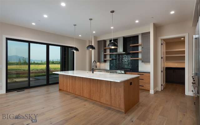 kitchen featuring a large island, light stone counters, backsplash, pendant lighting, and light wood-type flooring