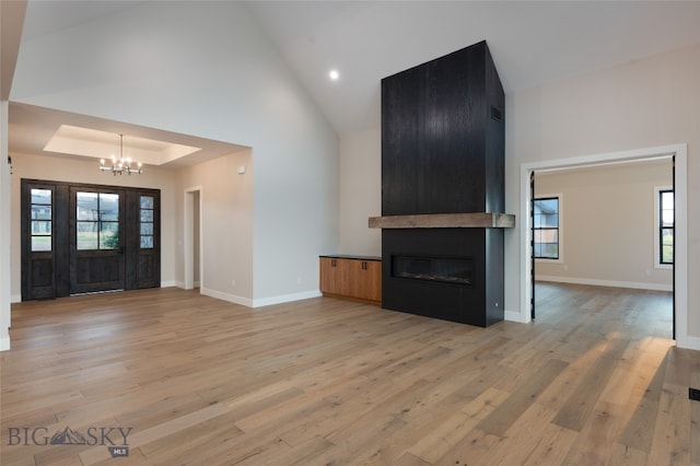 unfurnished living room featuring a wealth of natural light, a fireplace, light hardwood / wood-style floors, and an inviting chandelier