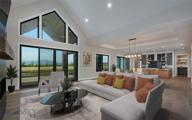 living room with light hardwood / wood-style floors, a raised ceiling, and a high ceiling