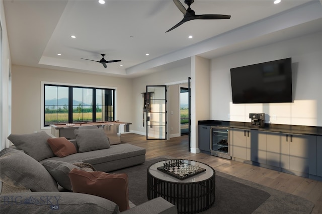 living room with a raised ceiling, ceiling fan, beverage cooler, and dark hardwood / wood-style floors