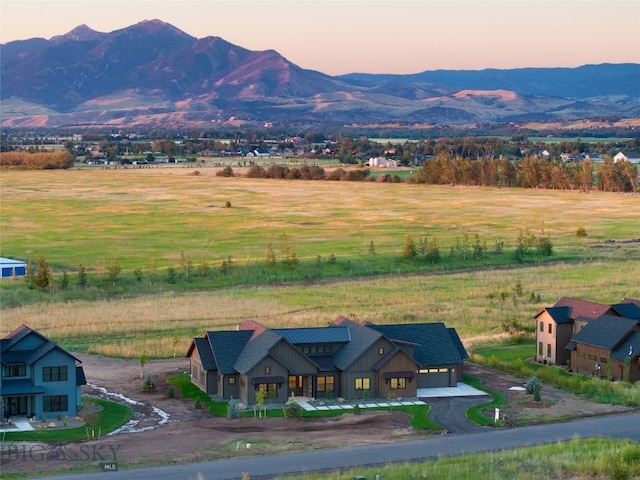 aerial view at dusk featuring a mountain view and a rural view