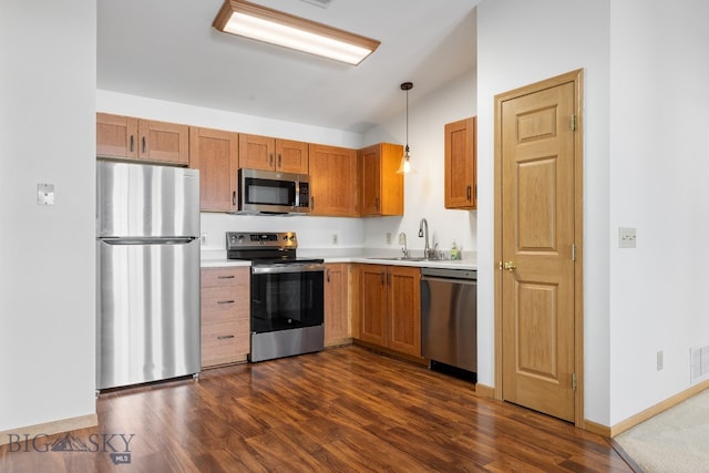 kitchen featuring sink, dark hardwood / wood-style flooring, hanging light fixtures, and appliances with stainless steel finishes