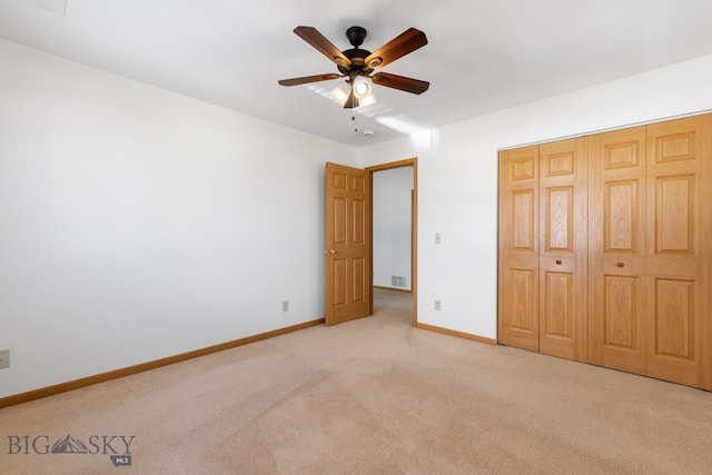 unfurnished bedroom featuring ceiling fan, light carpet, and a closet