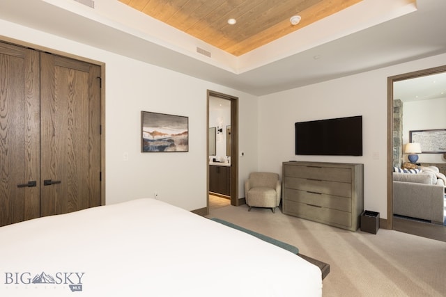 carpeted bedroom with a raised ceiling, ensuite bath, a closet, and wooden ceiling