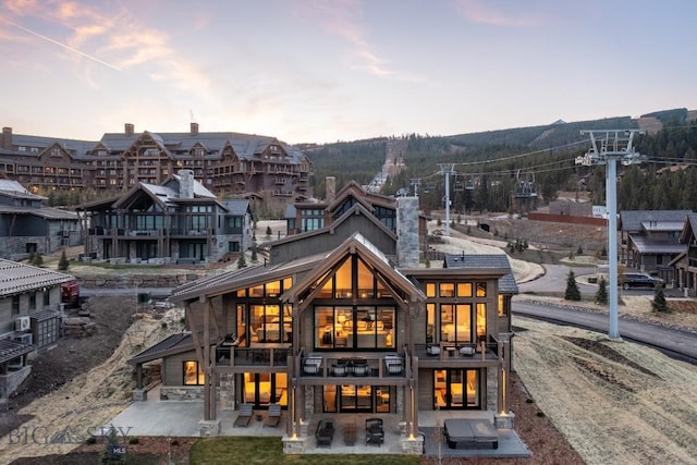 117 Martingale Frk Unit 6, Big Sky, MT 59716 - back of property at dusk featuring a patio, a balcony, and stone siding