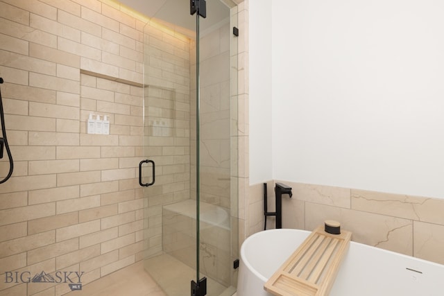 bathroom featuring separate shower and tub and tile walls