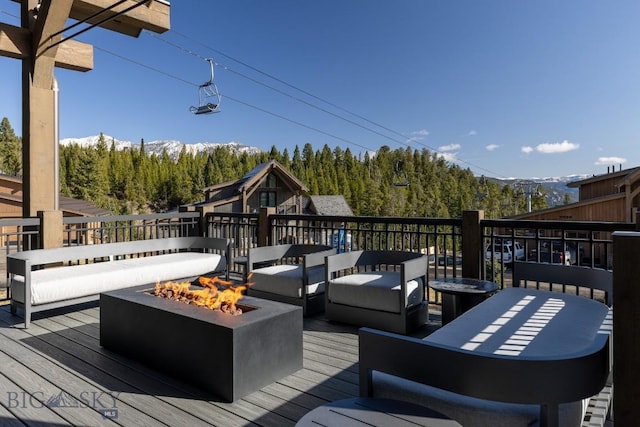 117 Martingale Frk Unit 6, Big Sky, MT 59716 - wooden terrace featuring a mountain view, an outdoor living space with a fire pit, and a forest view
