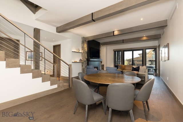 dining room with a fireplace, beam ceiling, and dark wood-type flooring