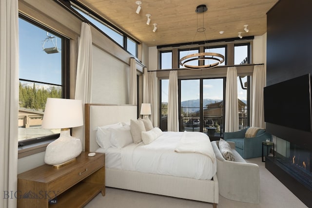 bedroom featuring a chandelier, a towering ceiling, track lighting, and wooden ceiling