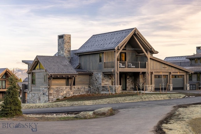 117 Martingale Frk Unit 6, Big Sky, MT 59716 - view of front of house with a balcony, stone siding, a chimney, an attached garage, and driveway