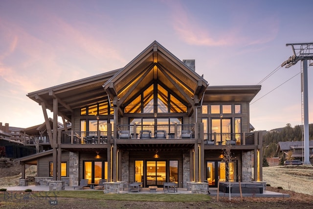 back house at dusk featuring a patio and a balcony