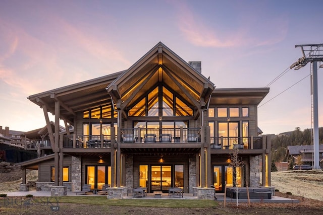 117 Martingale Frk Unit 6, Big Sky, MT 59716 - back of house at dusk featuring stone siding, a patio area, and a balcony