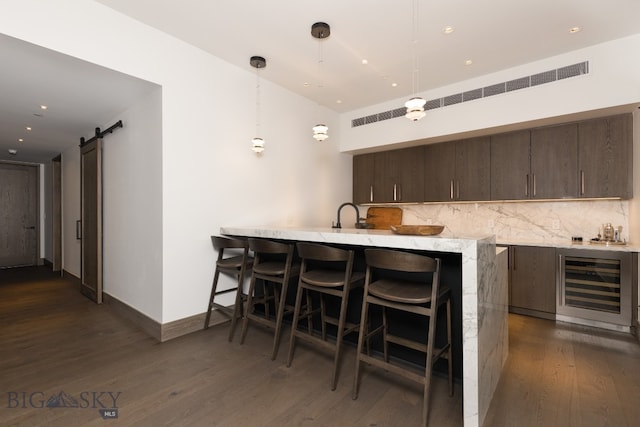 kitchen with kitchen peninsula, pendant lighting, a barn door, and wine cooler