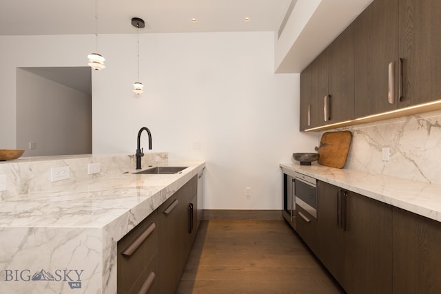 kitchen featuring decorative backsplash, light stone countertops, sink, pendant lighting, and dark hardwood / wood-style floors