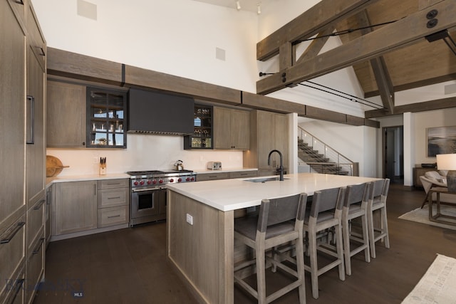 kitchen with sink, dark hardwood / wood-style flooring, double oven range, a kitchen bar, and a kitchen island with sink