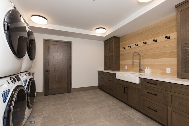 laundry room featuring stacked washer / dryer, sink, and light tile patterned floors