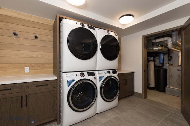 laundry area with cabinets, washing machine and dryer, stacked washer and dryer, and light tile patterned flooring