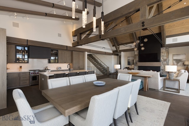 dining room featuring high vaulted ceiling, sink, dark hardwood / wood-style floors, a fireplace, and beamed ceiling