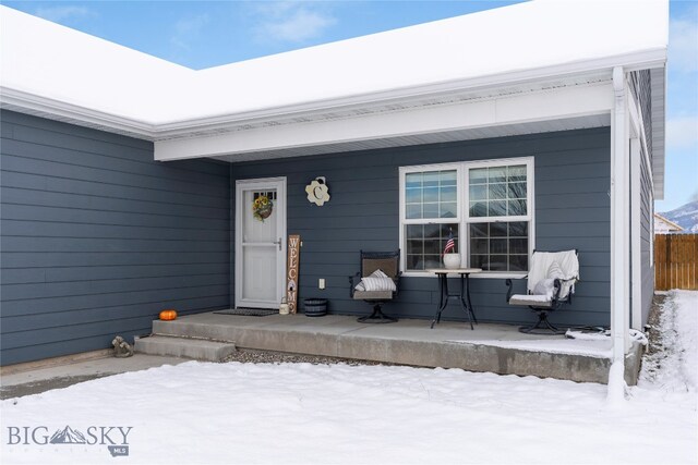 snow covered property entrance featuring a porch