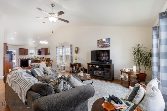 living room with hardwood / wood-style floors, ceiling fan with notable chandelier, and vaulted ceiling