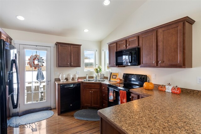 kitchen with black appliances, sink, hardwood / wood-style floors, and vaulted ceiling