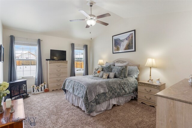 carpeted bedroom featuring ceiling fan, lofted ceiling, a wood stove, and multiple windows