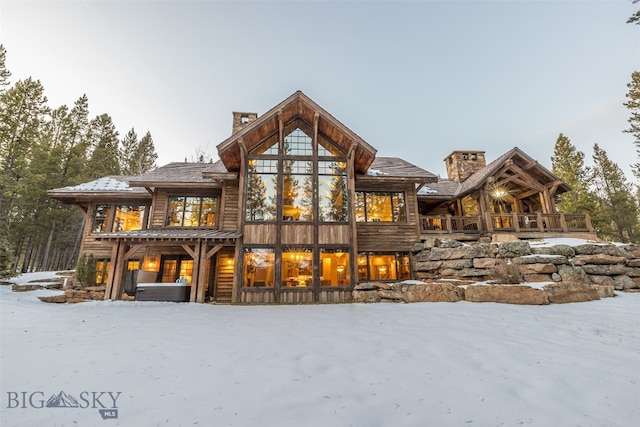 snow covered rear of property featuring a hot tub