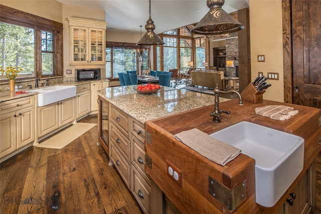 kitchen featuring cream cabinetry, dark hardwood / wood-style floors, light stone countertops, and decorative light fixtures