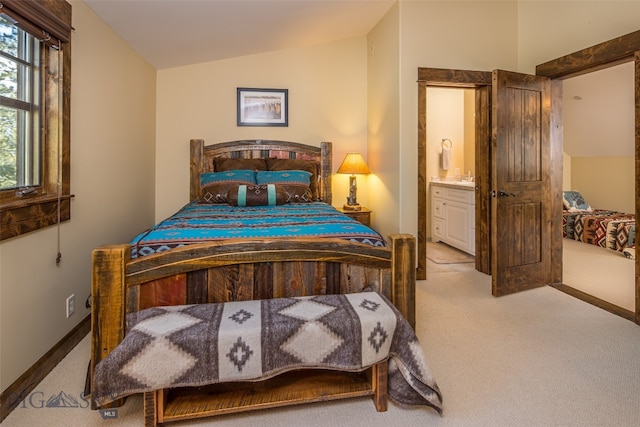 carpeted bedroom featuring connected bathroom, vaulted ceiling, and sink