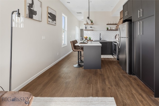 kitchen with a center island, stainless steel appliances, tasteful backsplash, dark hardwood / wood-style flooring, and a kitchen bar