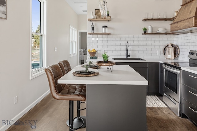 kitchen featuring a breakfast bar, sink, electric range, dark hardwood / wood-style floors, and a kitchen island