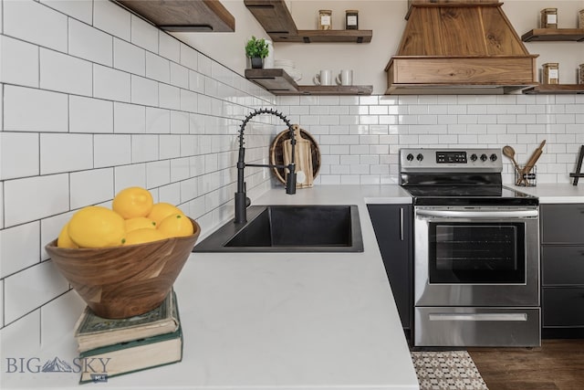 kitchen featuring stainless steel electric range, premium range hood, dark wood-type flooring, sink, and tasteful backsplash