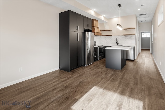 kitchen featuring stainless steel appliances, sink, hardwood / wood-style flooring, a kitchen island, and hanging light fixtures