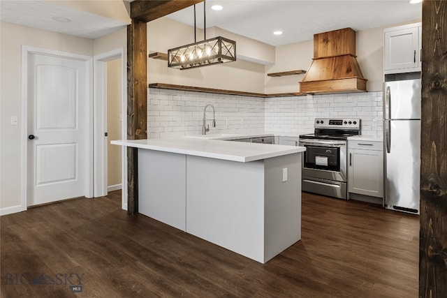 kitchen featuring kitchen peninsula, appliances with stainless steel finishes, sink, decorative light fixtures, and dark hardwood / wood-style floors