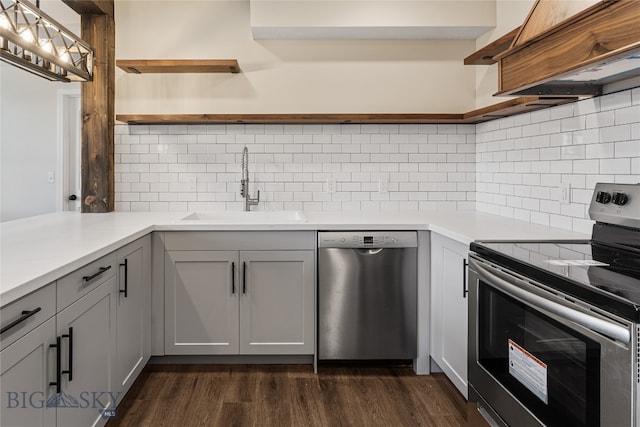 kitchen with dark hardwood / wood-style flooring, tasteful backsplash, gray cabinetry, stainless steel appliances, and sink