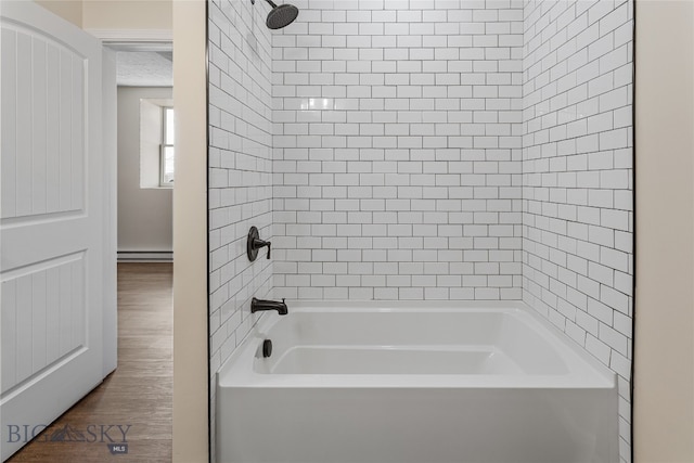 bathroom with wood-type flooring, tiled shower / bath combo, and baseboard heating