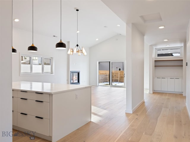 kitchen featuring a wealth of natural light, light hardwood / wood-style flooring, pendant lighting, and lofted ceiling