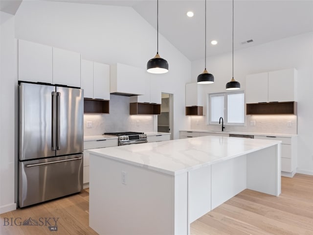 kitchen with a center island, stainless steel appliances, pendant lighting, light hardwood / wood-style floors, and white cabinets