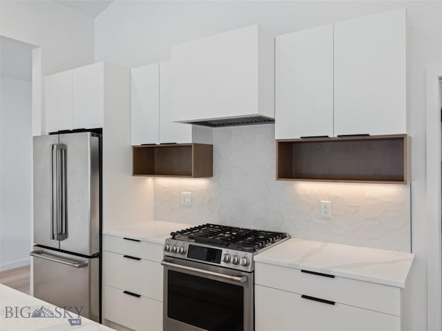 kitchen featuring white cabinets, decorative backsplash, light stone countertops, and high end appliances