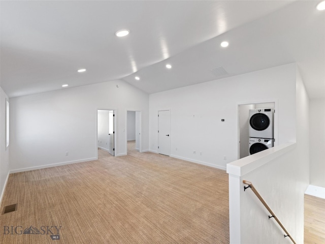 carpeted empty room featuring lofted ceiling and stacked washer / drying machine