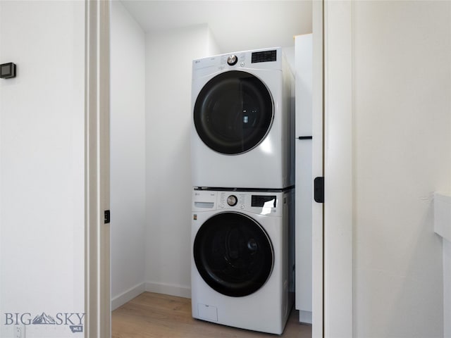 washroom featuring light hardwood / wood-style floors and stacked washer / dryer