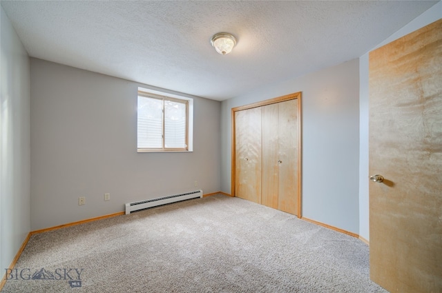 unfurnished bedroom with carpet, a closet, a textured ceiling, and a baseboard heating unit