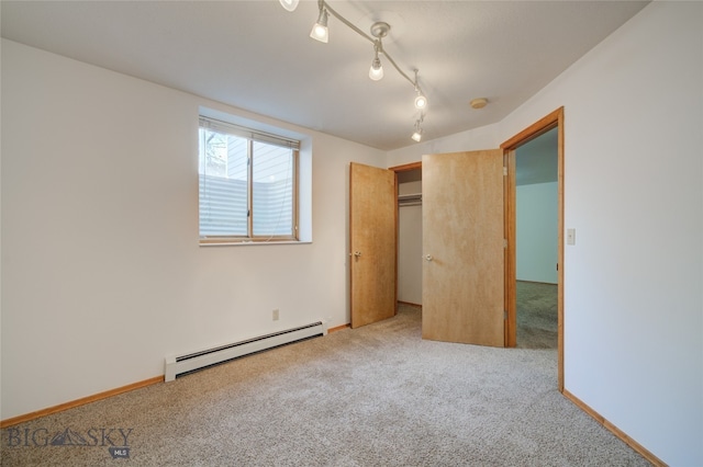 unfurnished bedroom with baseboard heating, a closet, carpet floors, and rail lighting