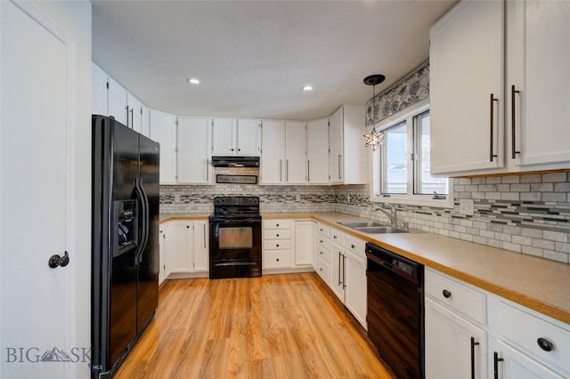 kitchen featuring light wood-type flooring, sink, black appliances, white cabinetry, and hanging light fixtures