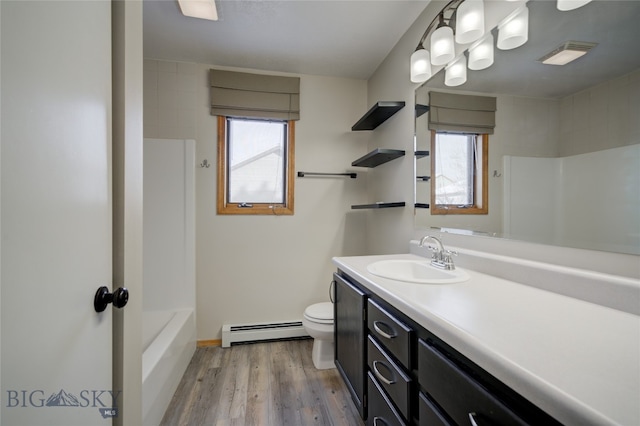 bathroom featuring baseboard heating, a wealth of natural light, toilet, and hardwood / wood-style flooring