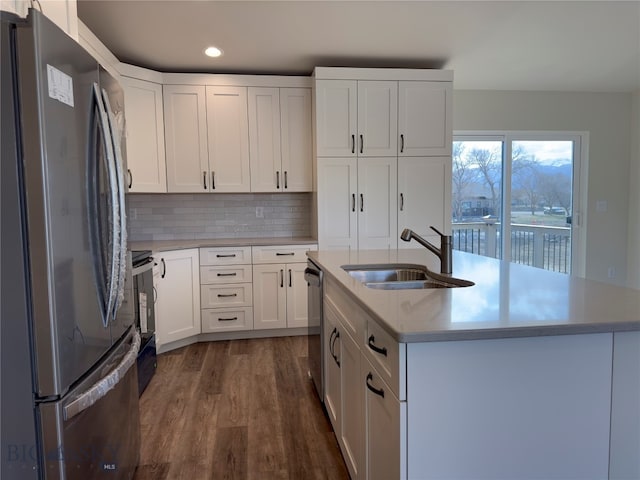 kitchen featuring white cabinetry, sink, stainless steel appliances, dark hardwood / wood-style flooring, and a center island with sink