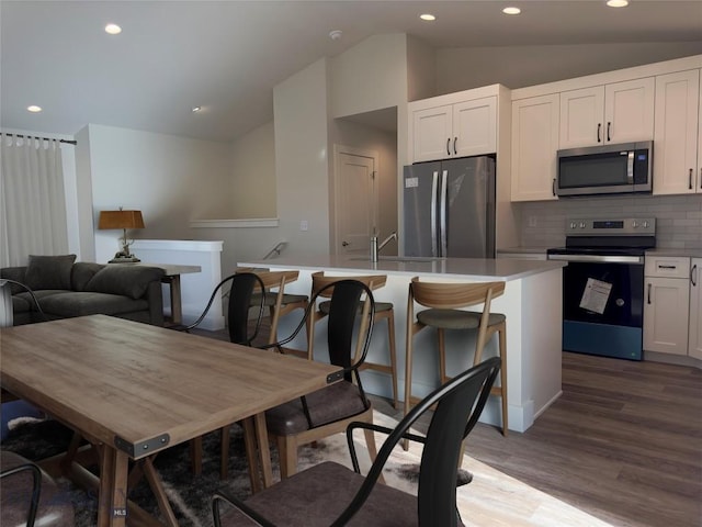 206 Otis Ave, Ennis, MT 59729 - kitchen with stainless steel appliances, lofted ceiling, decorative backsplash, white cabinets, and wood finished floors
