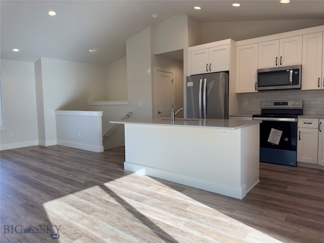 kitchen featuring white cabinets, appliances with stainless steel finishes, lofted ceiling, and an island with sink