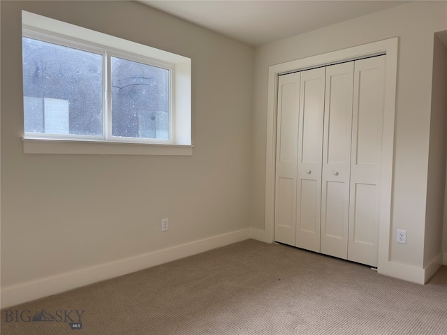 unfurnished bedroom featuring multiple windows, light carpet, and a closet